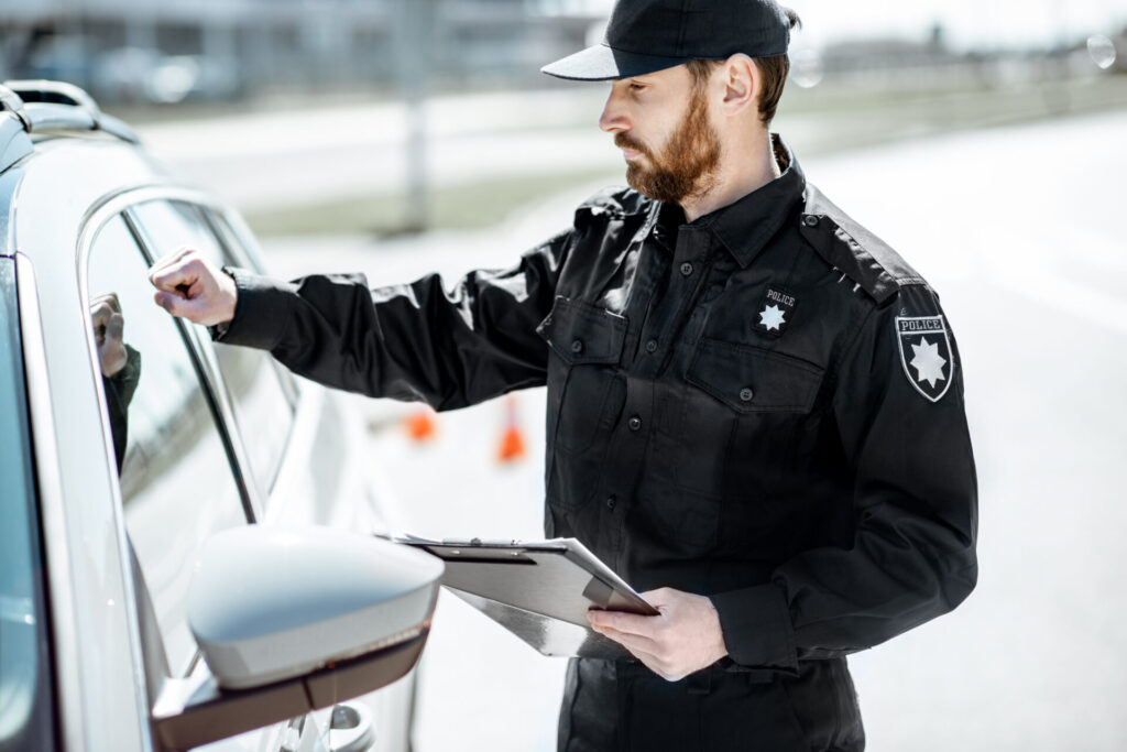 Policeman knocking at the window to a car driver, stopping the car for the offense